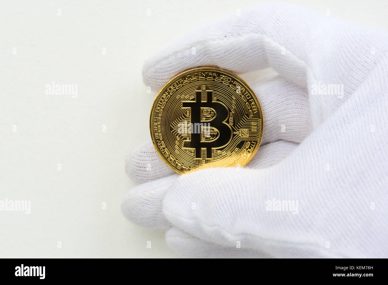 Hand mit weißen Handschuhen mit einem goldenen Bitcoin Stockfoto