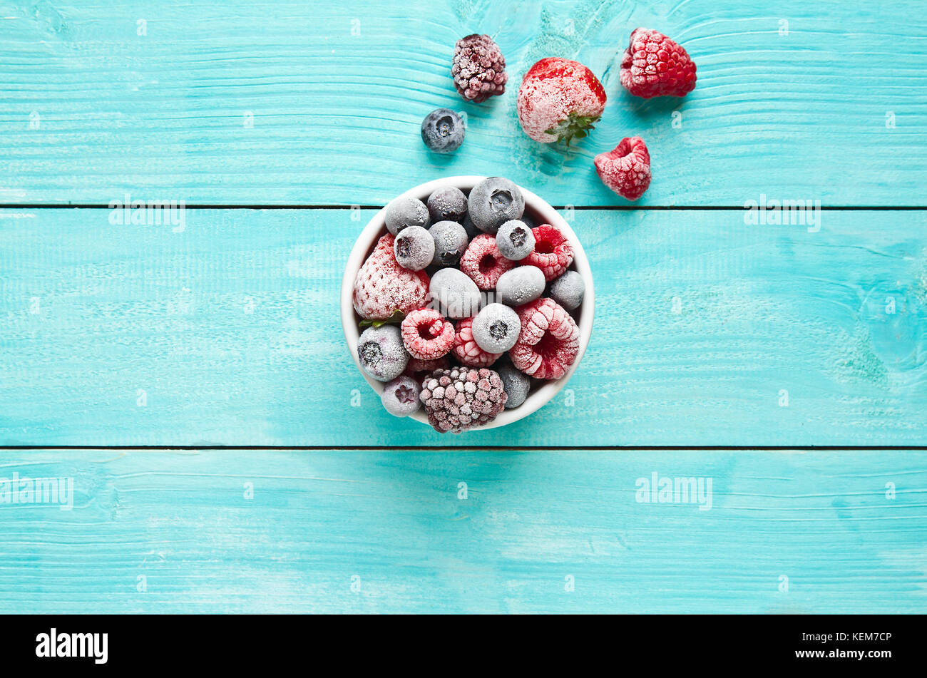 Verschiedene gemischte gefrorene Beeren in einer Schüssel auf blauem Hintergrund Stockfoto