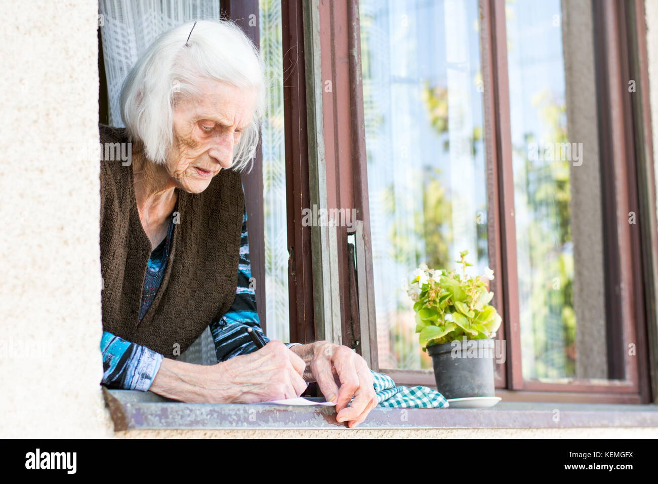 Ältere Frau Unterzeichnung Ruhestand prüfen auf dem Fenster zu Hause Stockfoto