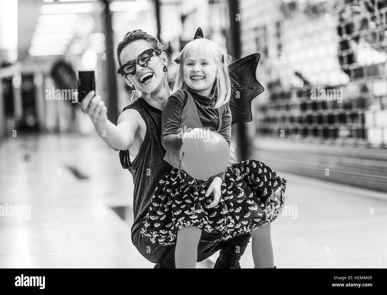Trick oder Festlichkeit. Gerne stilvolle Mutter und Kind in bat Kostüme zu Halloween in der Mall mit Digitalkamera unter selfie Stockfoto