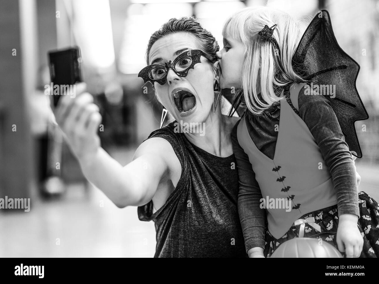 Trick oder Festlichkeit. Portrait von trendigen Mutter und Tochter in der Fledermaus Kostüme zu Halloween in der Mall, scary halloween selfie auf der Digitalkamera. Stockfoto