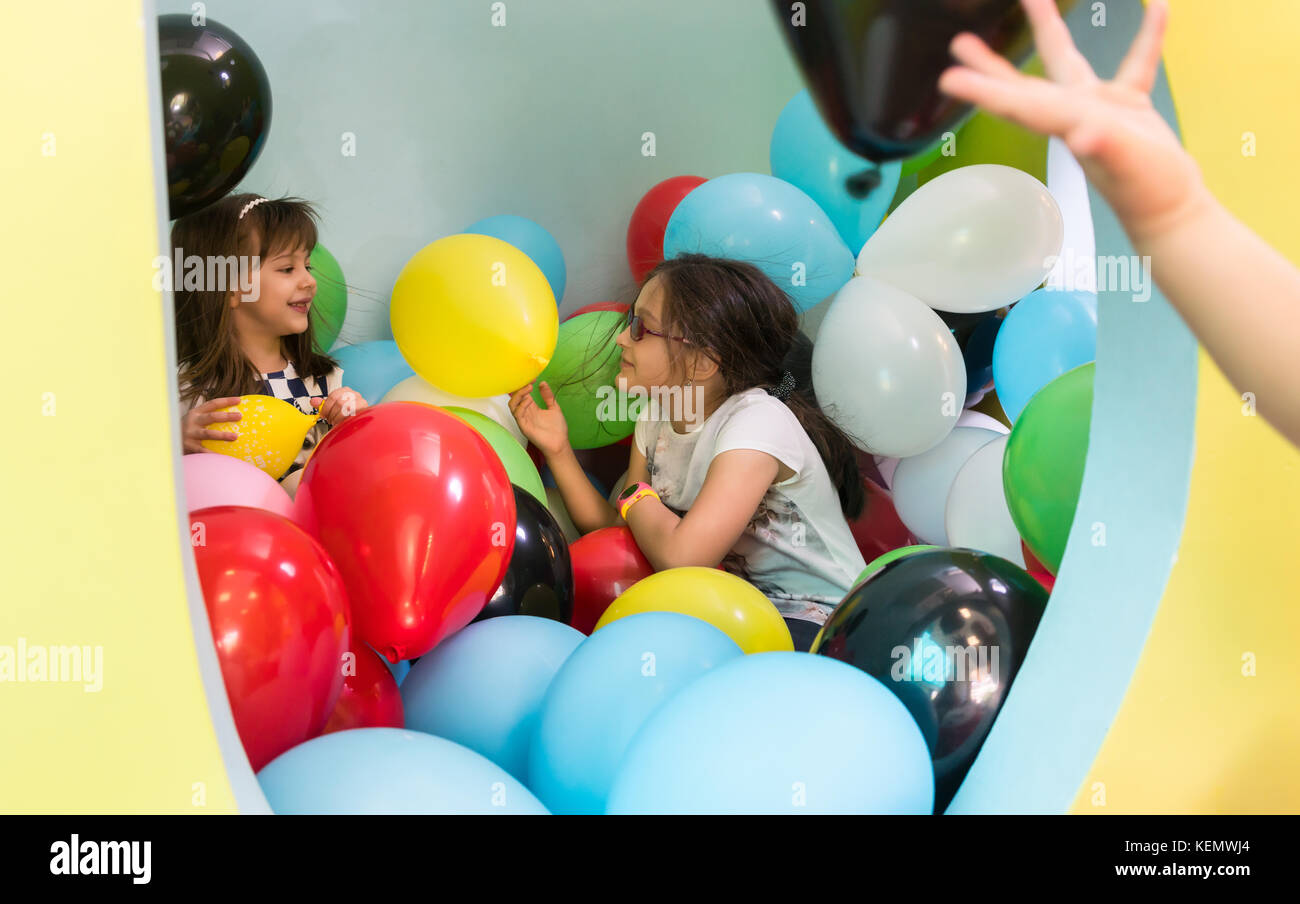 Zwei nette Mädchen sprechen, während Sie mit bunten Luftballons Stockfoto