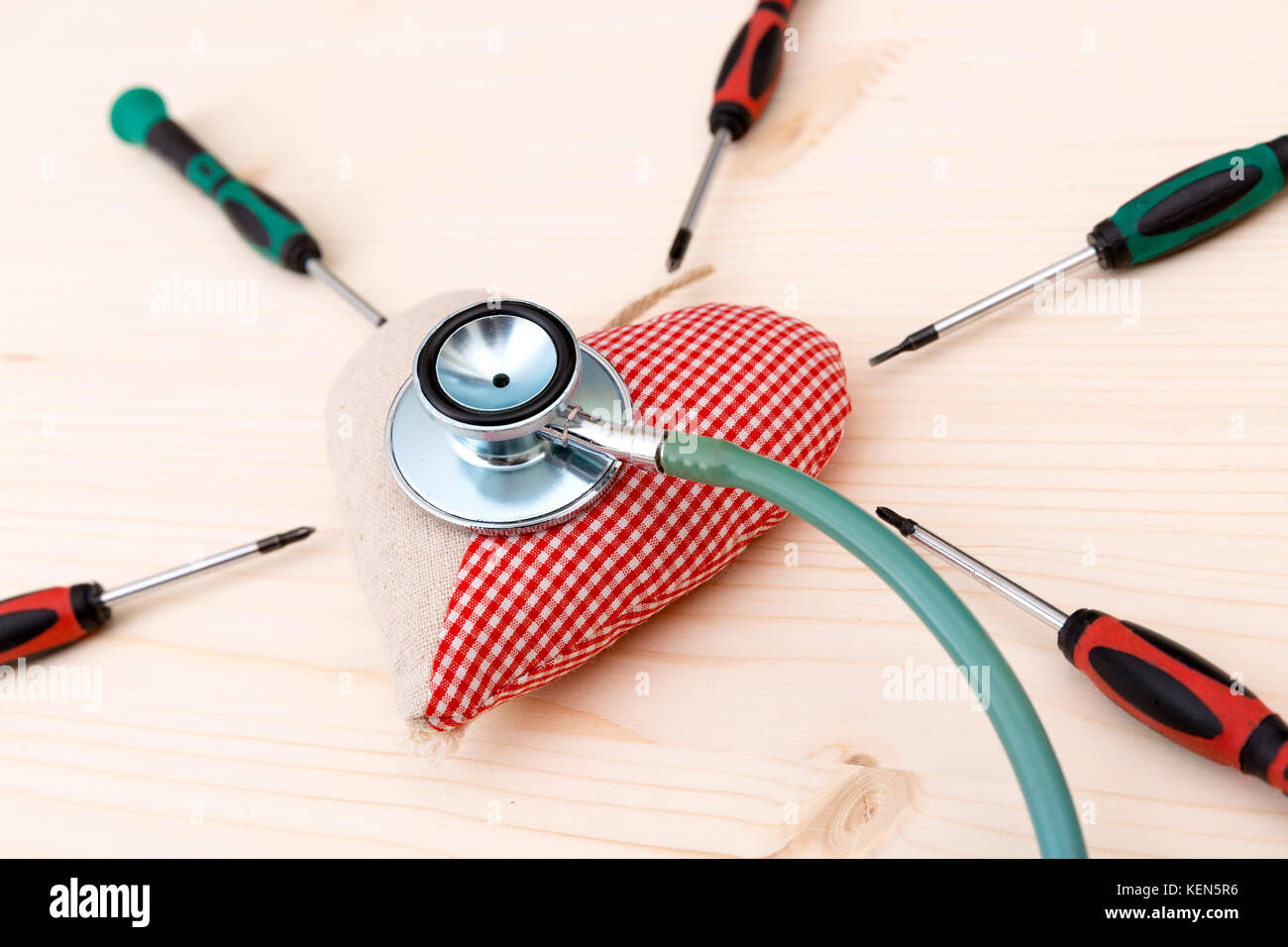 Stoff rotes Herz, Stethoskop und srewdrivers herum auf Holztisch - Gesundheit und Gesundheitswesen Konzept Stockfoto
