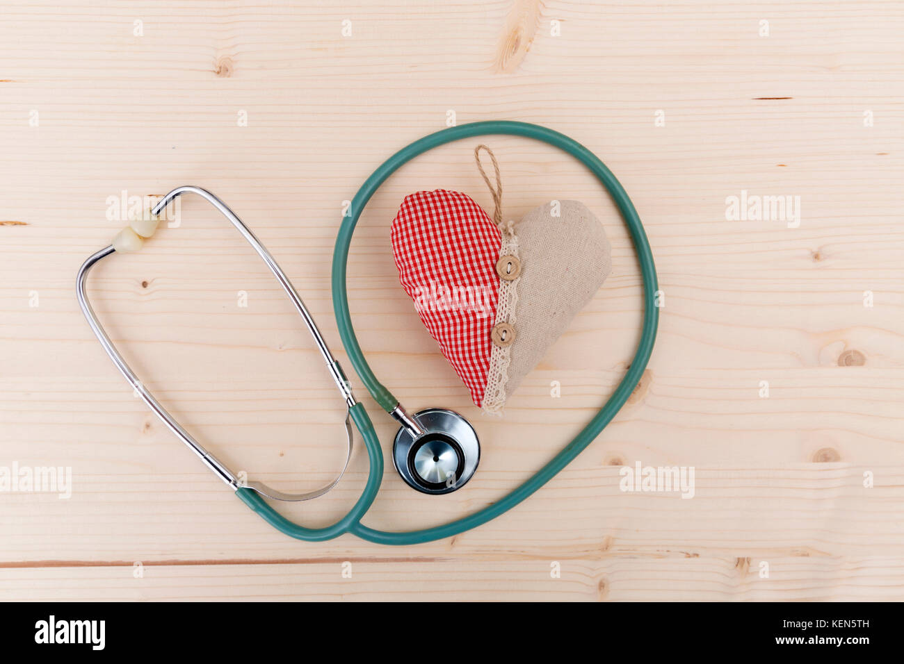Stethoskop und rotem Stoff Herz liegen auf Holztisch. healthcare, Kardiologie und medizinisches Konzept Stockfoto