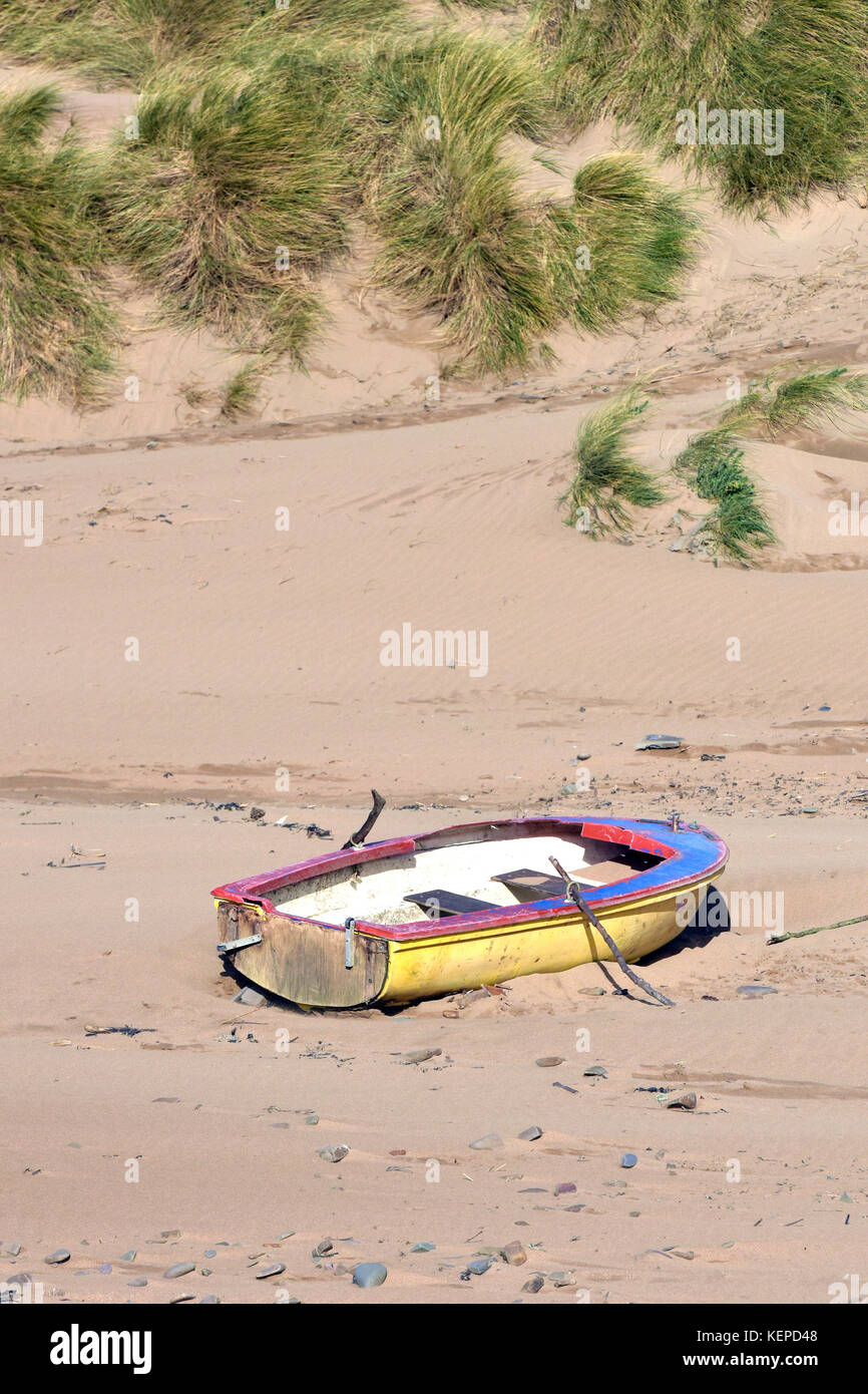 Ein altes Boot, das auf einen Strand an der Flut Mark oder Litze Linie trieb unter den Sanddünen an der sandigen Küste an der Bude in Cornwall hat. Stockfoto