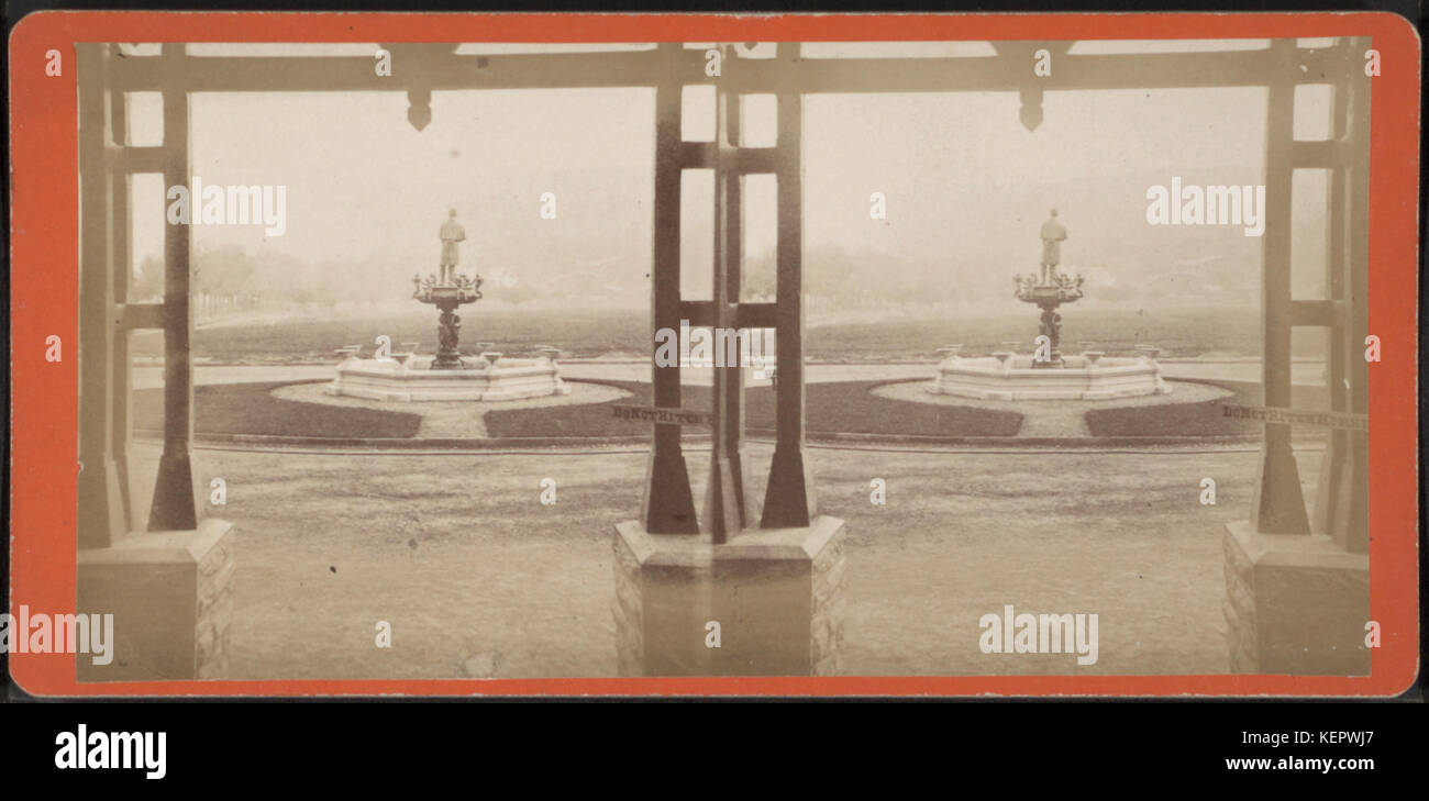 Dieses Foto von Ackerman Bros erfasst den Blick auf einen Brunnen vom Inneneingang eines Gebäudes und zeigt architektonische Details und Landschaftsgestaltung im Freien. Das Bild betont die Verbindung zwischen der Struktur und ihrer Umgebung. Stockfoto