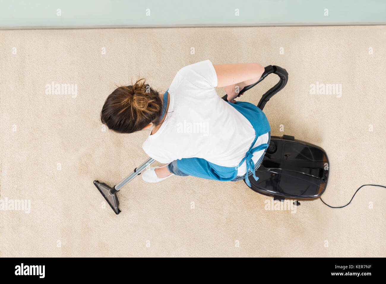 Junge weibliche Hausmeister in Uniform absaugen, Stockfoto