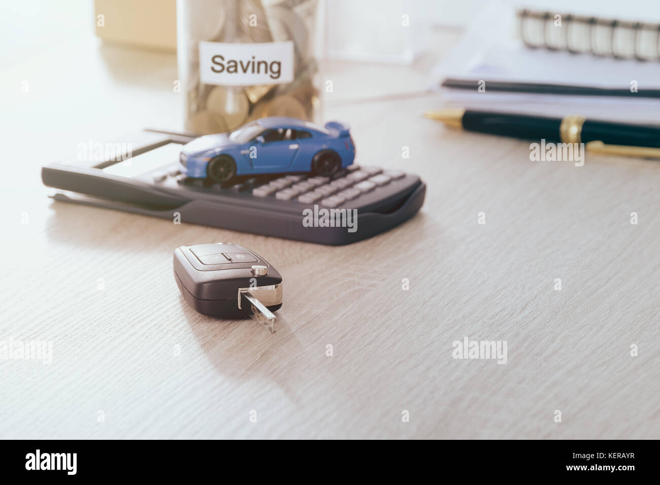 Car Key remote auf dem Schreibtisch mit unscharfen Auto Spielzeug auf Rechner und sparen Sie bares Geld in den jar-Bank: Konzept für Wartung Kosten und Steuern Auto, warmen Ton Filter. Stockfoto
