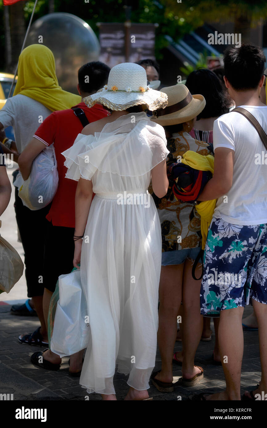 Chinesische Touristen. Um sich von der Masse ab. Frau in einem weißen Kleid aus Chiffon. Volle Länge. Kuckucksei aus Stockfoto
