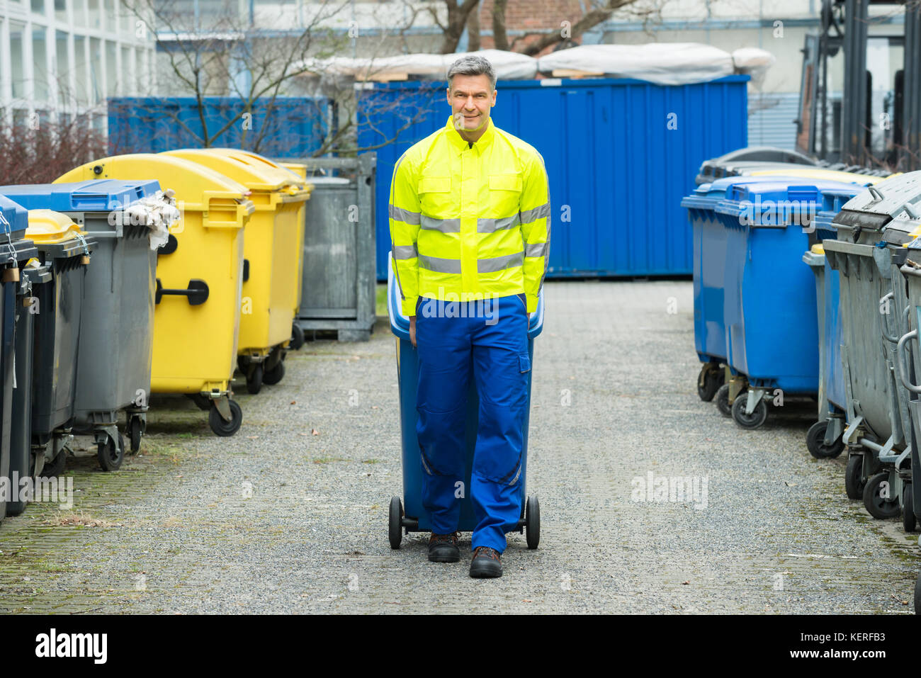 Happy männlichen Arbeitnehmer gehen mit Mülltonne auf der Straße bei Tag Stockfoto