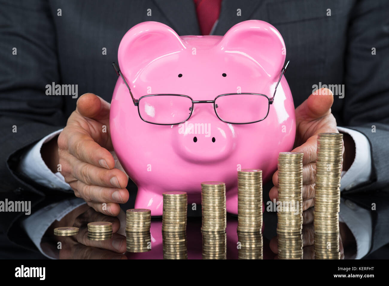 Nahaufnahme der Geschäftsmann hand schützenden Sparschwein und Münzen am Schreibtisch Stockfoto Nahaufnahme der Geschäftsmann hand schützenden Sparschwein und Münzen am Schreibtisch Stockfoto