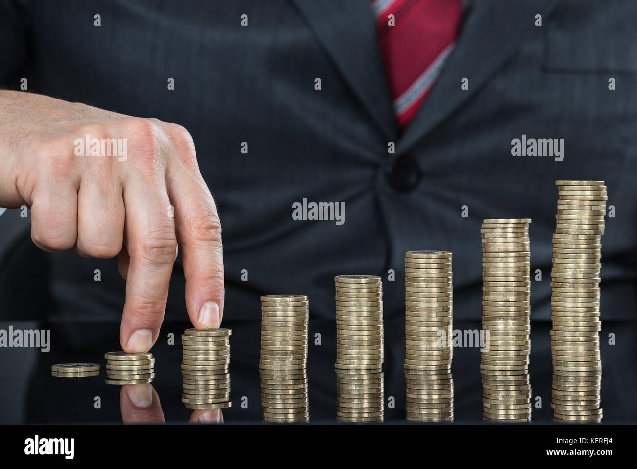 Nahaufnahme der Geschäftsmann Finger wandern auf Stapel von Münzen am Schreibtisch Stockfoto