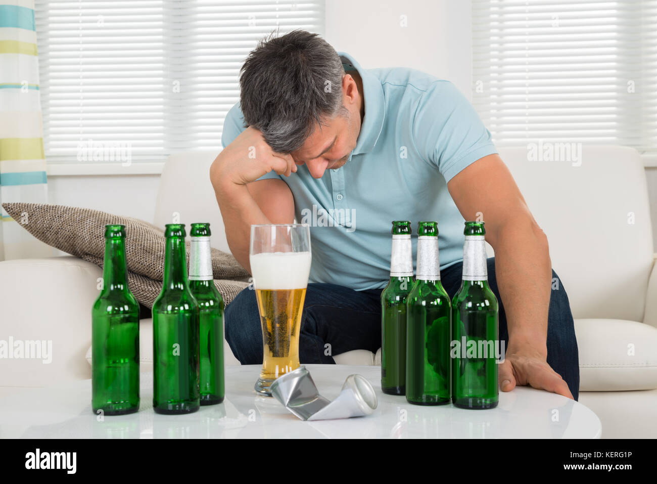 Reifen Mann sitzt auf einem Sofa Vor der Flasche Bier auf Tisch Stockfoto