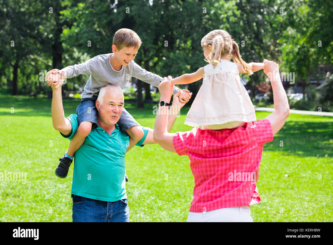 Gerne alten Großeltern genießen Spaß Piggyback Ride mit Enkelkindern zusammen In Park Stockfoto