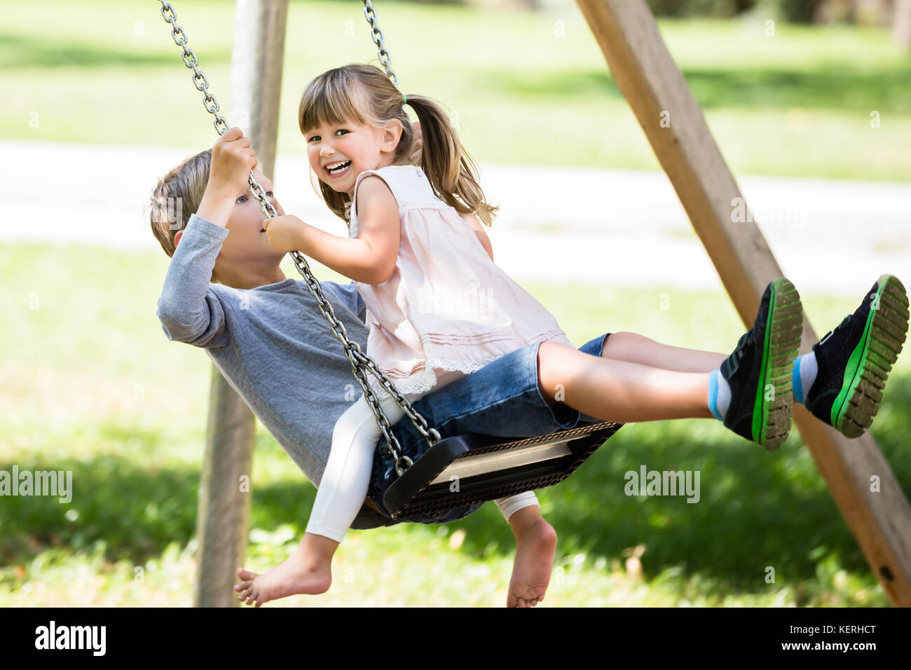 Glückliche Kinder - Jungen und Mädchen auf Swing im Park Stockfoto