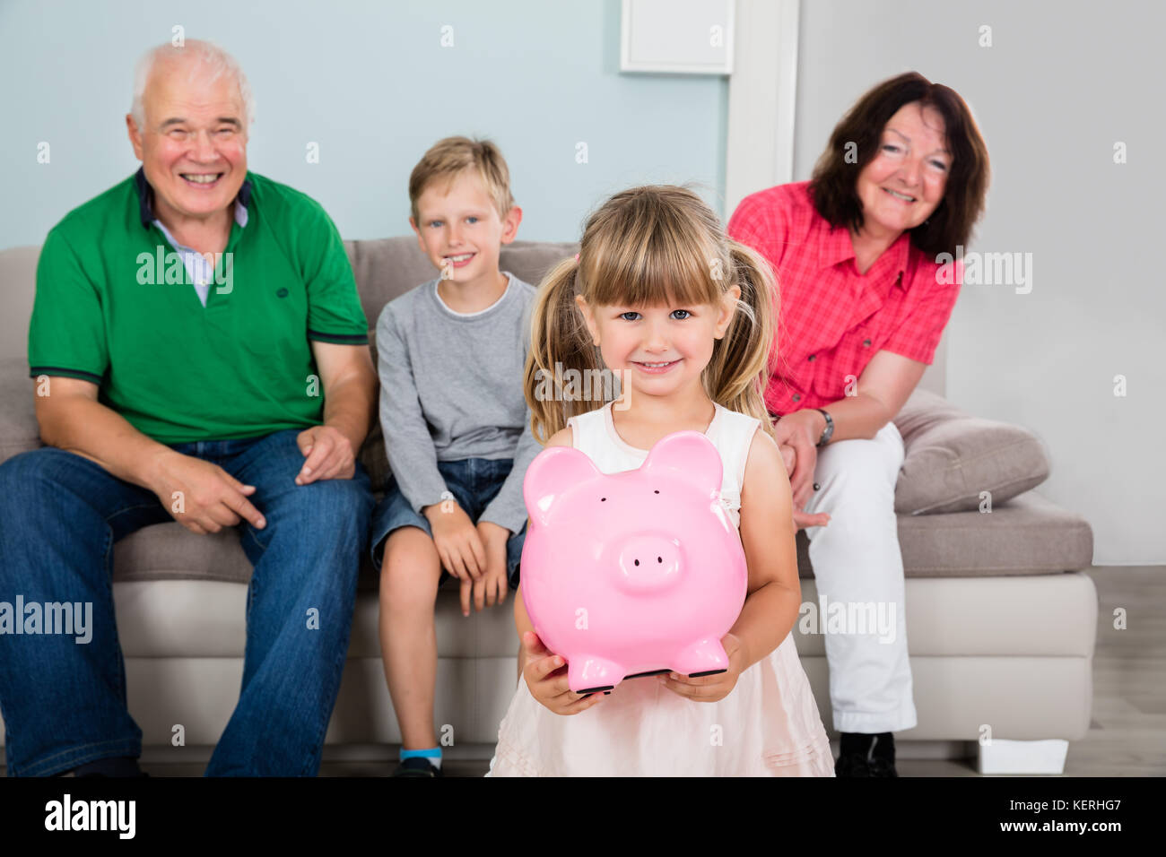 Kid Holding piggy Bank Geld sparen Vor Familie Stockfoto