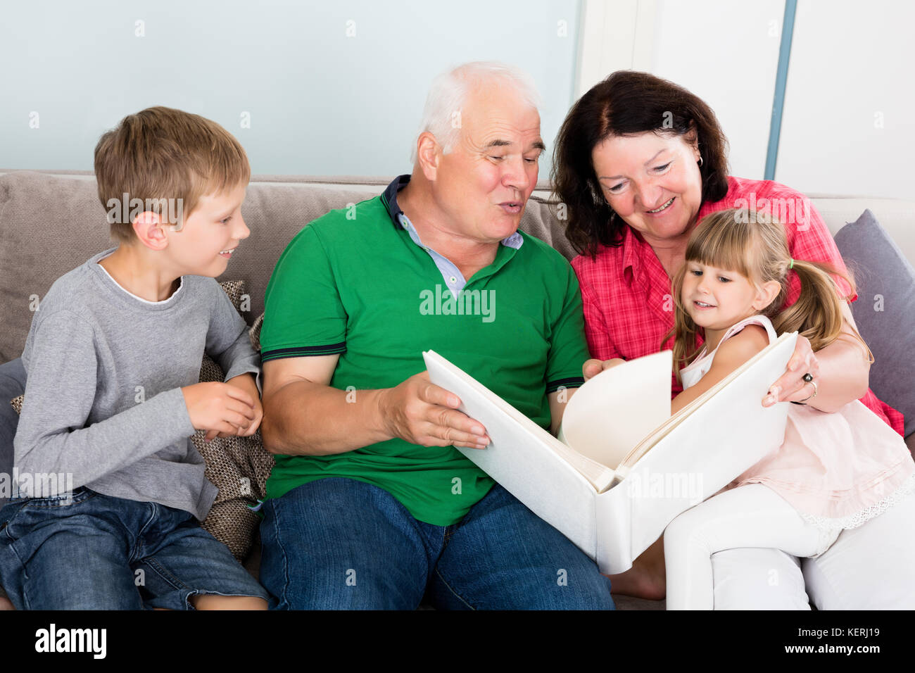 Familie bei Fotobuch mit Enkelkindern zusammen zu Hause Suchen Stockfoto