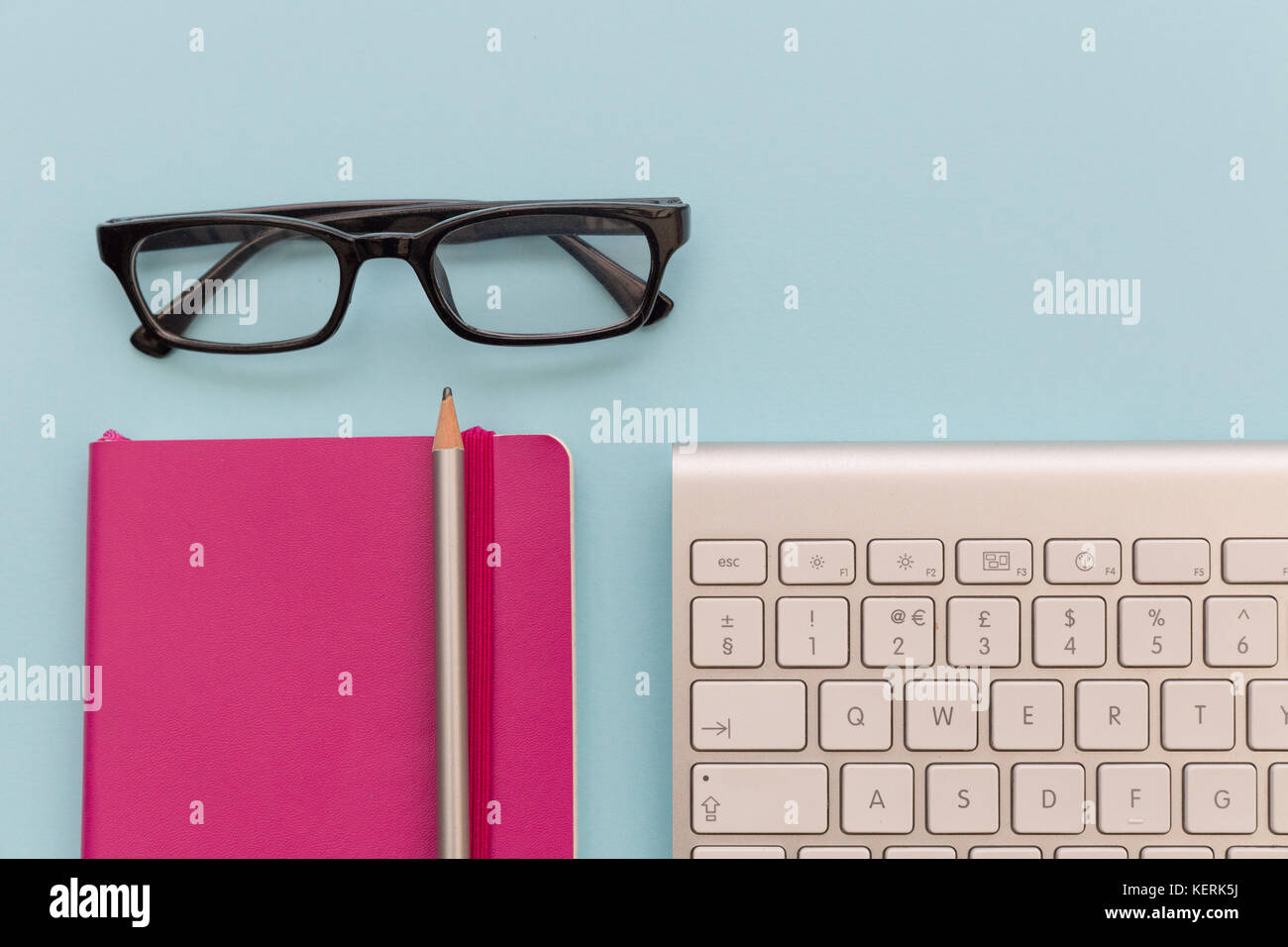 Computer Tastatur, Lesebrillen und Notebook auf blauem Hintergrund Stockfoto