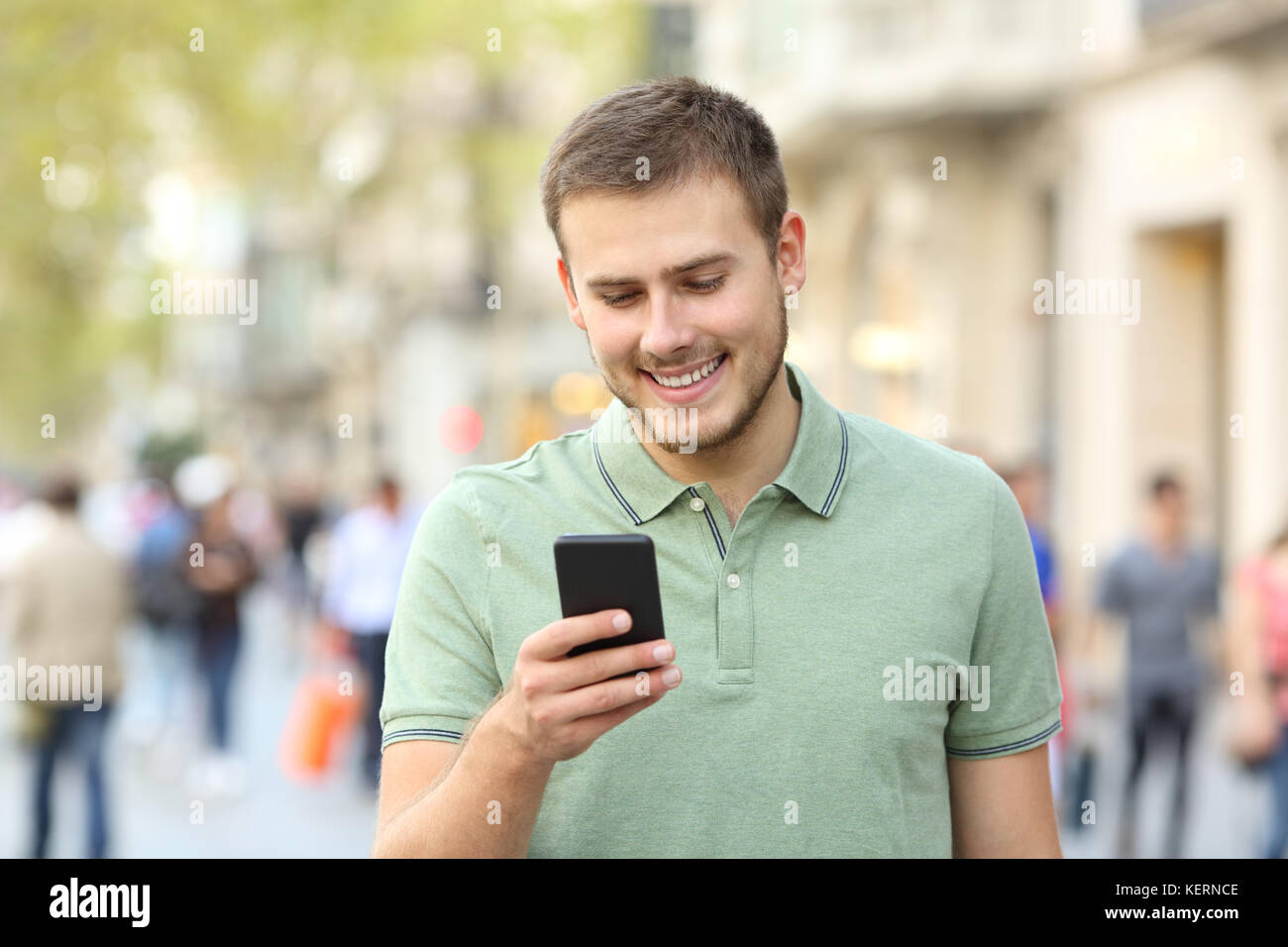Vorderansicht Porträt eines Mannes zu Fuß und mit einem Smart Phone auf der Straße Stockfoto