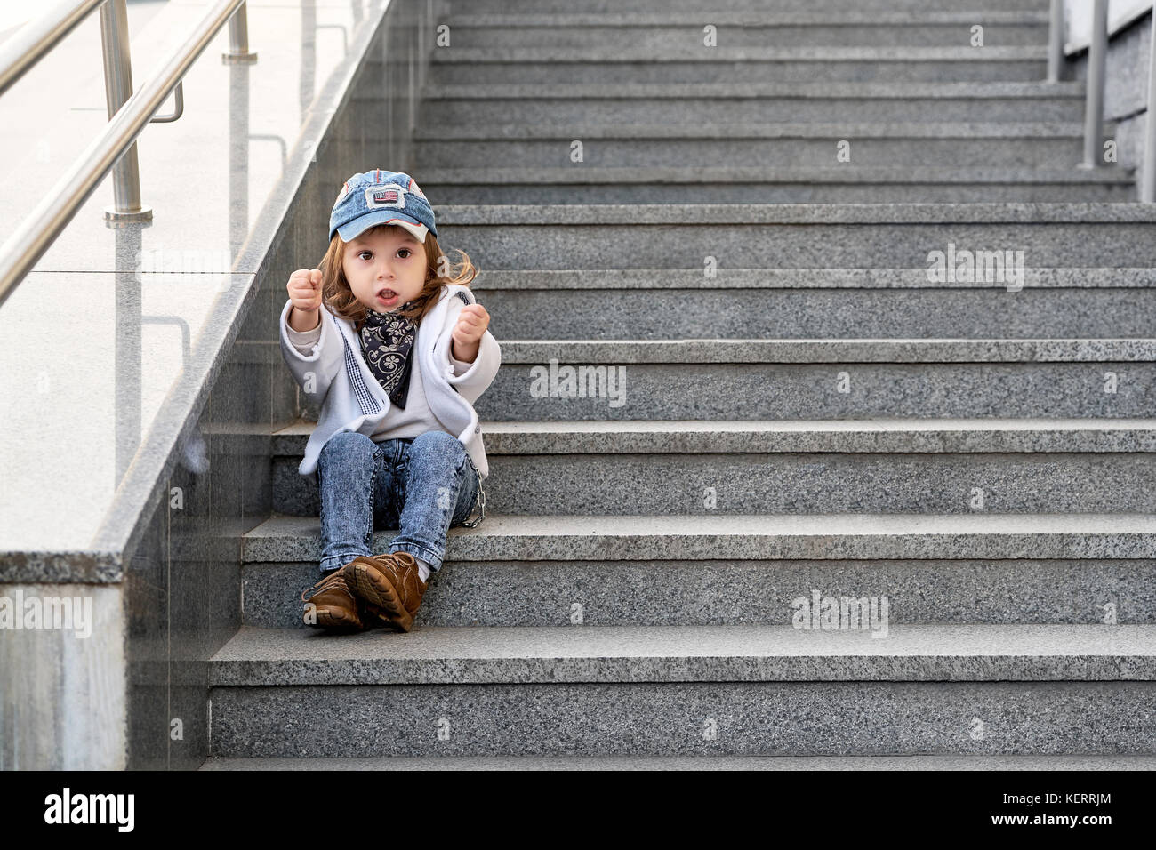 Modell Kind hip-hop sitzen auf der Treppe im Freien. Mädchen Street fashion jeans Kleidung Stockfoto