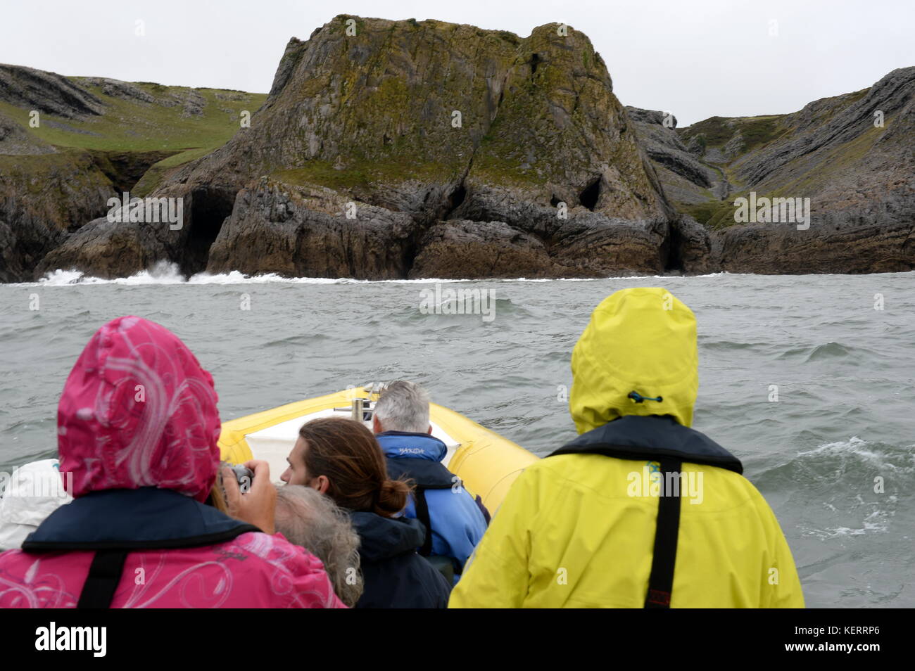Anzeigen der Gower vom Boot aus, eine kleine Gruppe von Menschen fotografieren und bewundern Sie die Küste aus einer Rippe Stockfoto