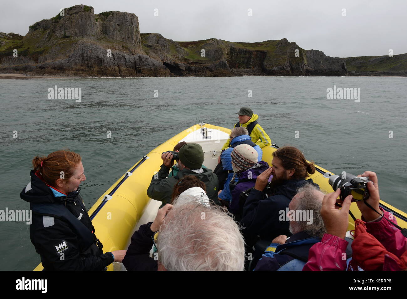 Anzeigen der Gower vom Boot aus, eine kleine Gruppe von Menschen fotografieren und bewundern Sie die Küste aus einer Rippe Stockfoto