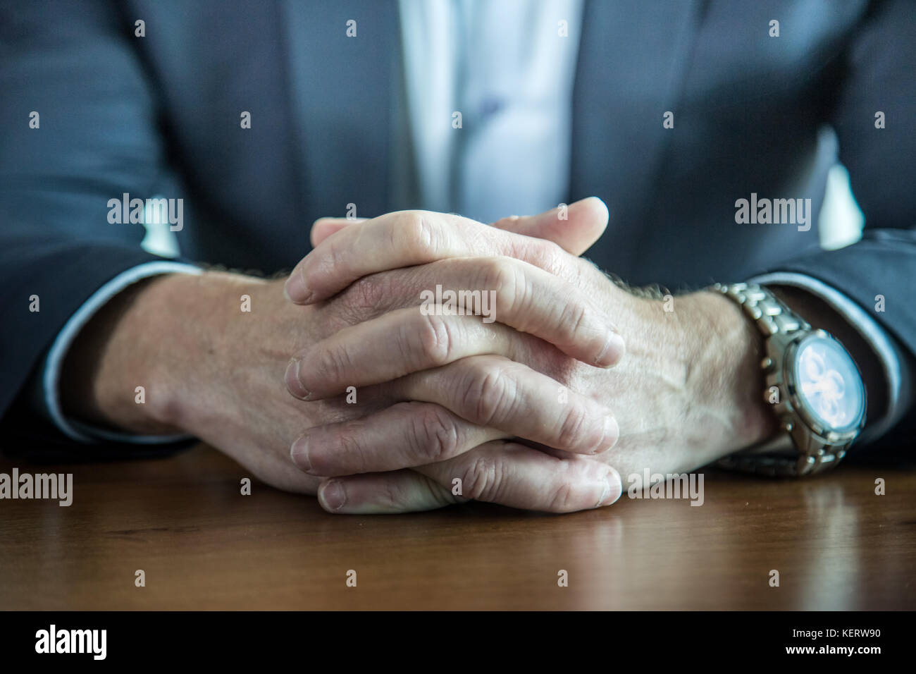 Nahaufnahme der Geschäftsmann halten Hände mit den Fingern auf dem Tisch gekreuzt Stockfoto