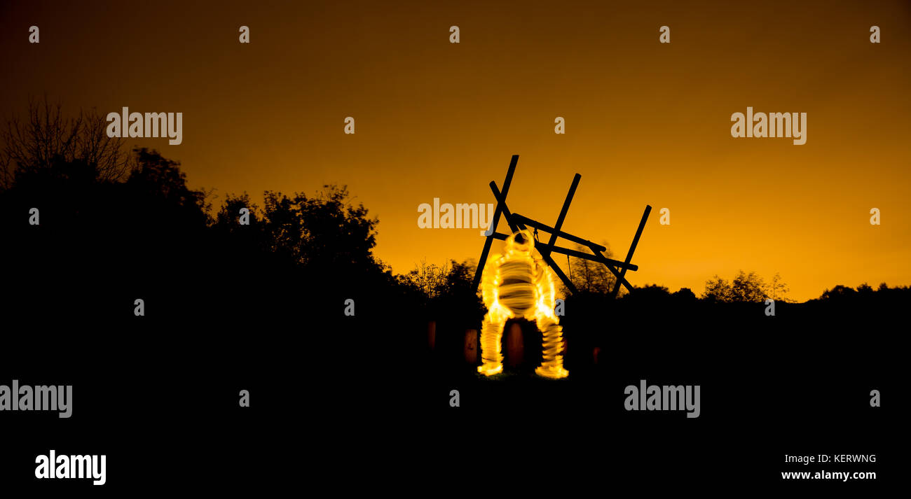 Eine seltsam Unheimliche, glühende Abbildung sichtbar ist sitzt draußen in der dunklen Silhouette gegen einen Hintergrund als das Licht des Tages verschwindet. Stockfoto