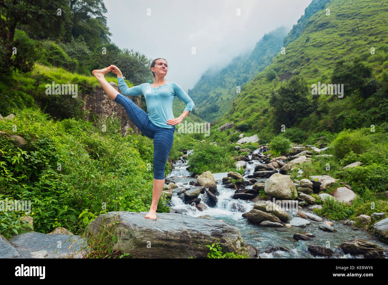 Frau tut Ashtanga Vinyasa Yoga Asana im Freien am Wasserfall Stockfoto