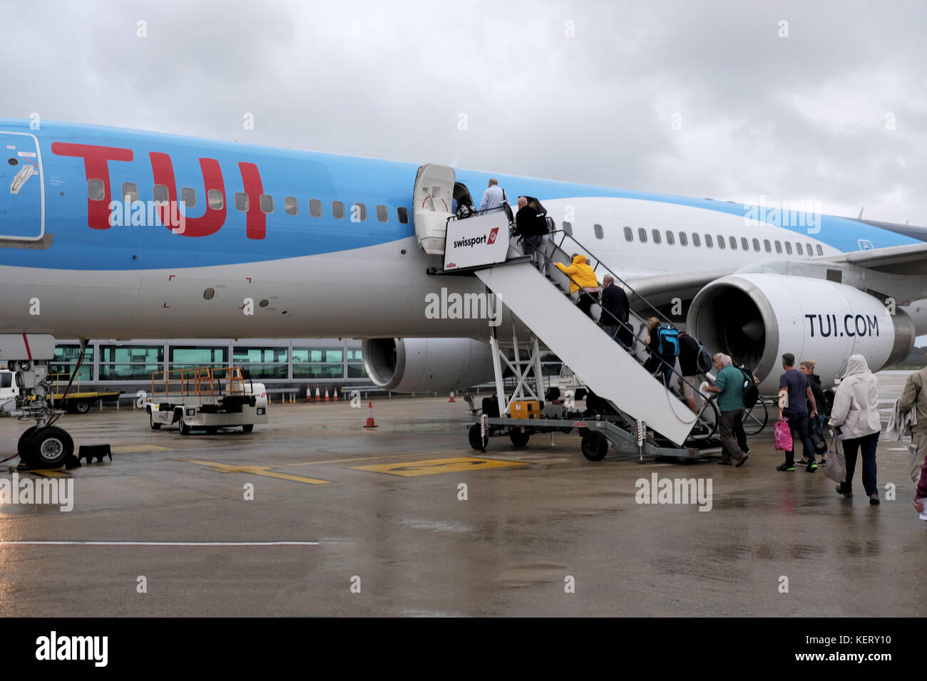 Ein TUI-Flugzeug, das im Regen auf dem Flughafenvorfeld am Flughafen Bristol steht. Das Flugzeug wird von Passagieren bestiegen, die zu einem Urlaub abreisen Stockfoto