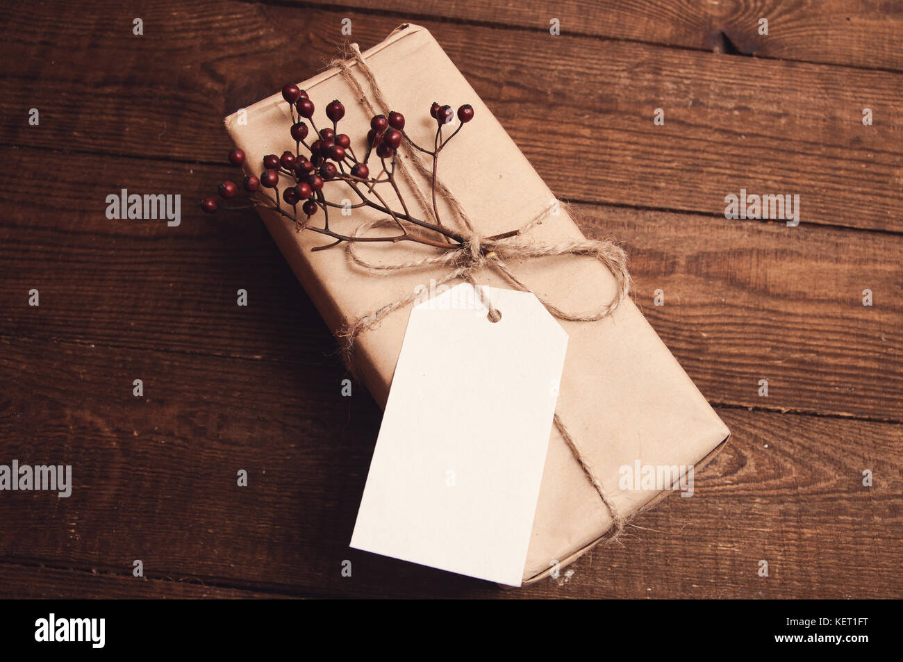 Geschenk verpackt in Kraftpapier mit einem Zweig der trockene Beeren an der Oberseite in der Nähe der Umschlag Stockfoto