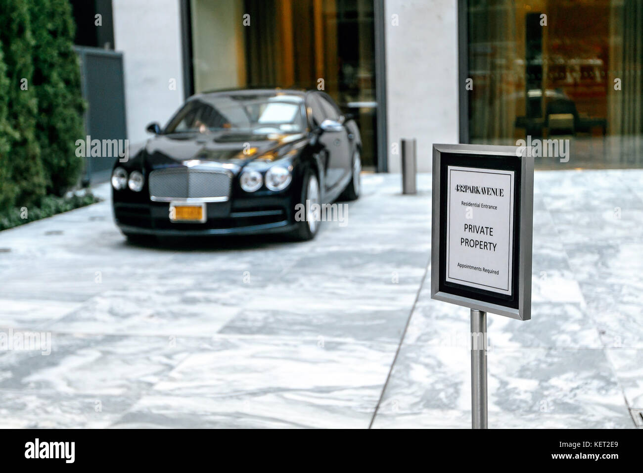 Hinweis in der Nähe der Einfahrt zum posh 432 Park Avenue Residential Tower in New York City mit einem geparkten schwarzen Bentley. Stockfoto