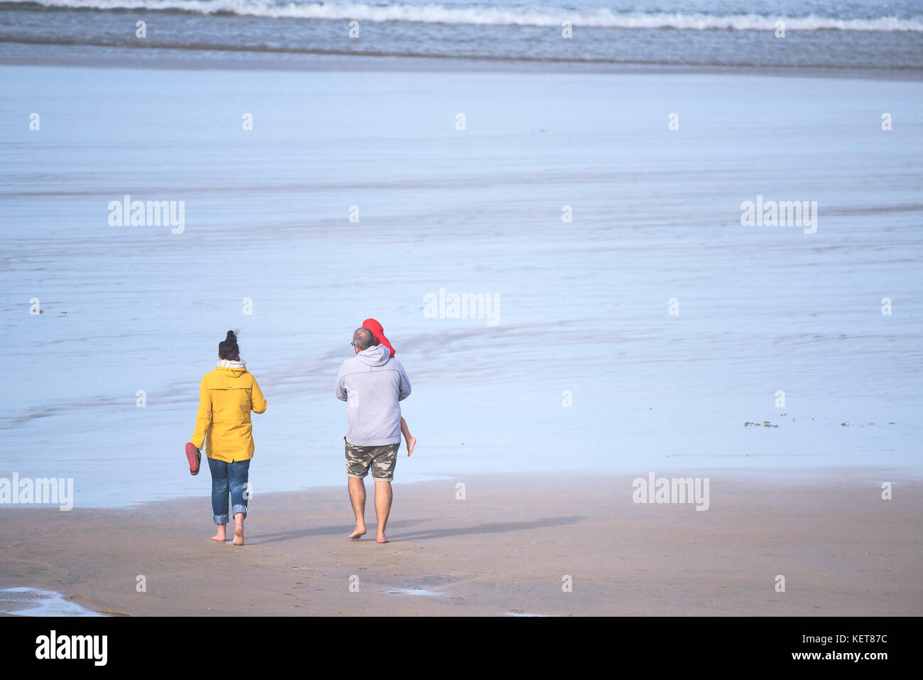 Urlauber zu Fuß am Strand - eine Familie von Urlaubern zu Fuß am Fistral Beach in Newquay, Cornwall. Stockfoto