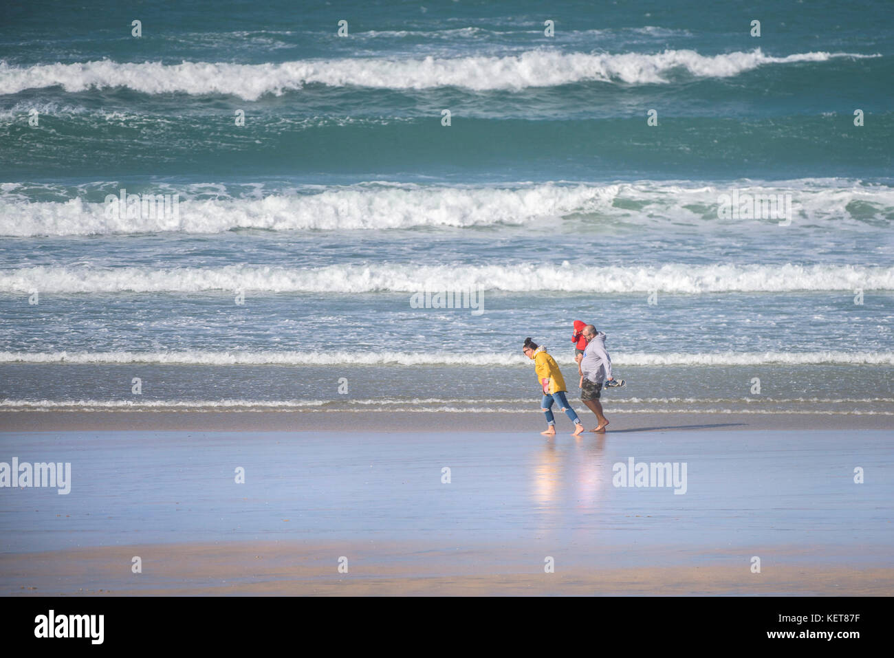 UK Wetter Windy Conditons - eine Familie, die in starken Wind am Fistral Beach in Newquay, Cornwall. Stockfoto