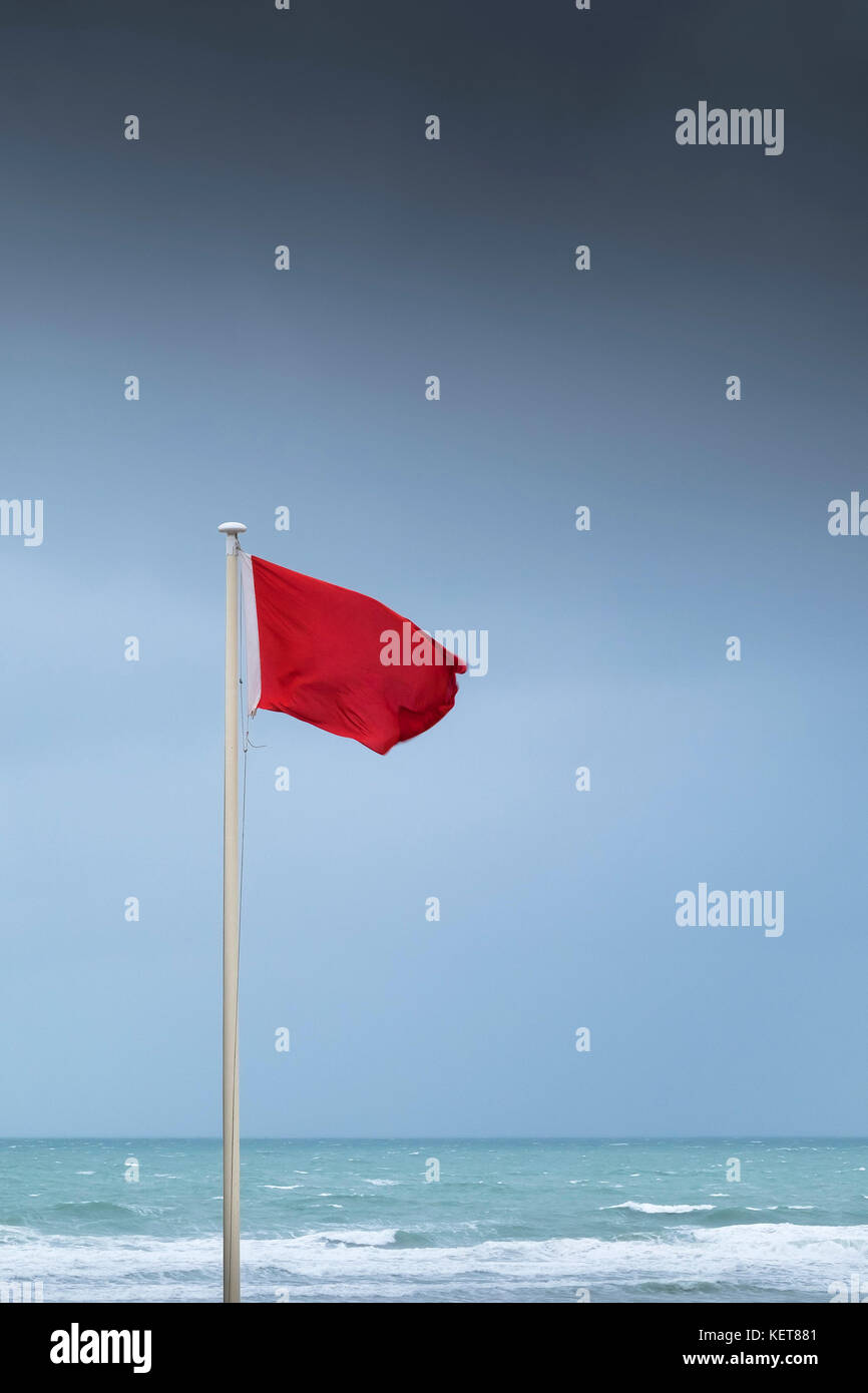 Rote Fahne - eine rote Flagge in High Wind am Fistral Beach Newquay Cornwall fliegen. Stockfoto