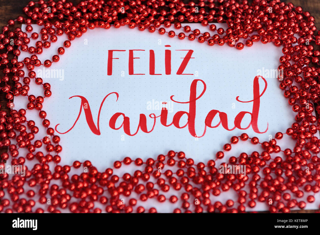 Frohe Weihnachten, der Botschaft der Bischöfe in Spanisch mit rote Dekoration Stockfoto