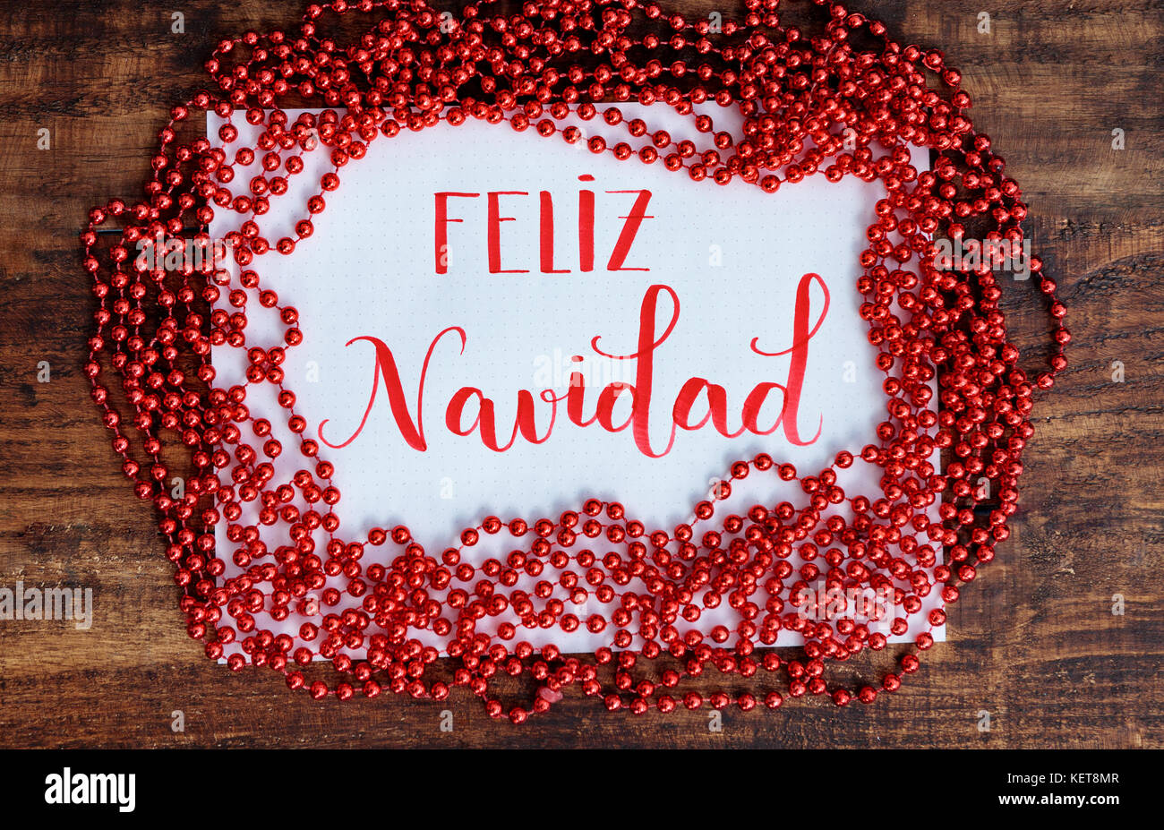 Frohe Weihnachten, der Botschaft der Bischöfe in Spanisch mit rote Dekoration Stockfoto