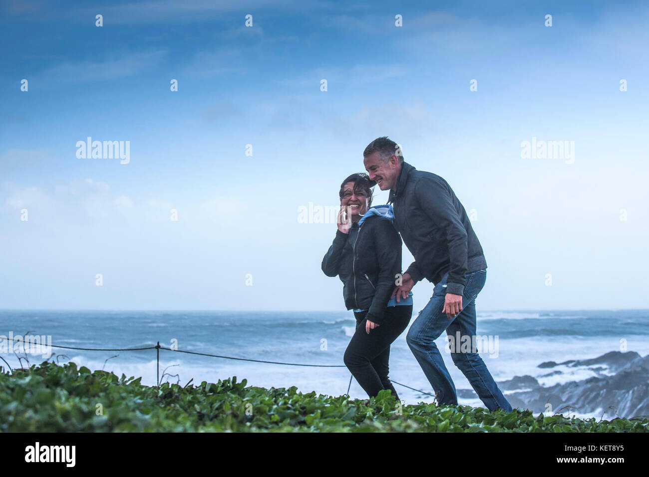 UK Wetter Sturm Brian - ein paar Lachen und genießen Wandern in stormforce Winde als Sturm Brian bringt schwere Wetter an der Küste von North Cornwall. Stockfoto