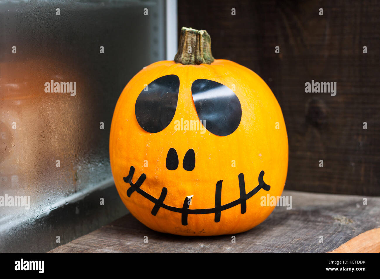 Scary Halloween pumpking mit schwarzen Augen und einem schwarzen Lächeln auf einem Holztisch Stockfoto