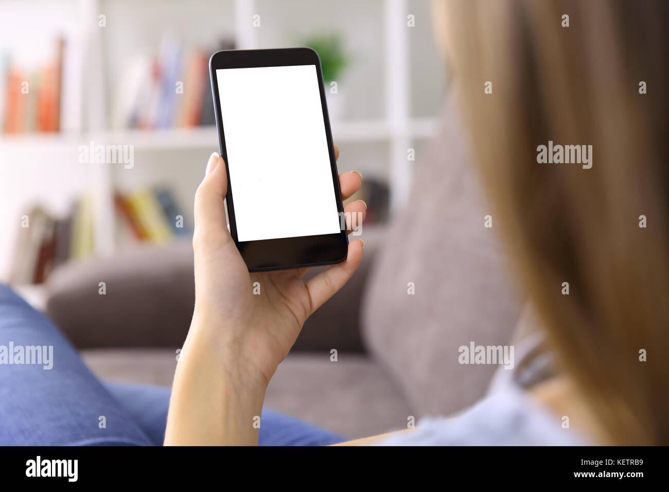 Ansicht von Hinten Nahaufnahme einer Frau hand mit einem smart phone mit leerer Bildschirm liegen auf der Couch zu Hause Stockfoto