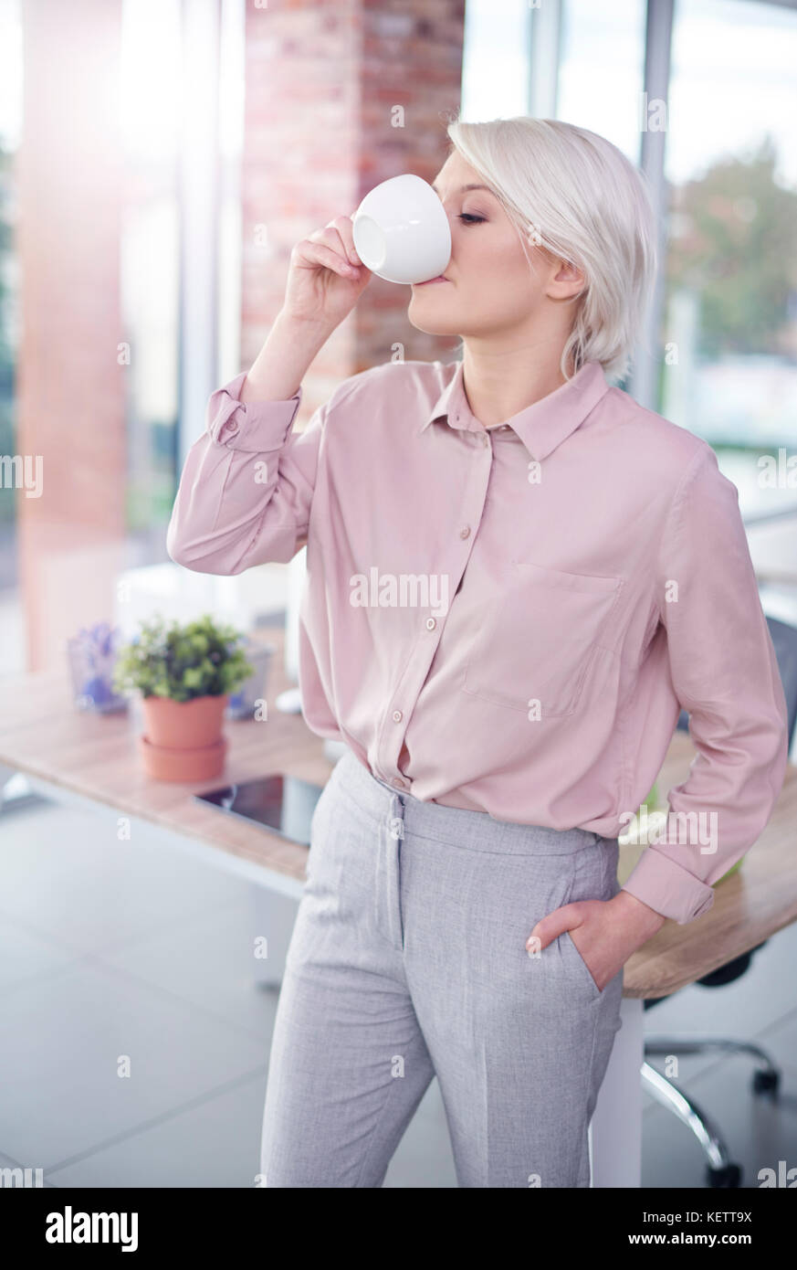 Frau mit Hand in der Tasche, einen Kaffee Stockfoto