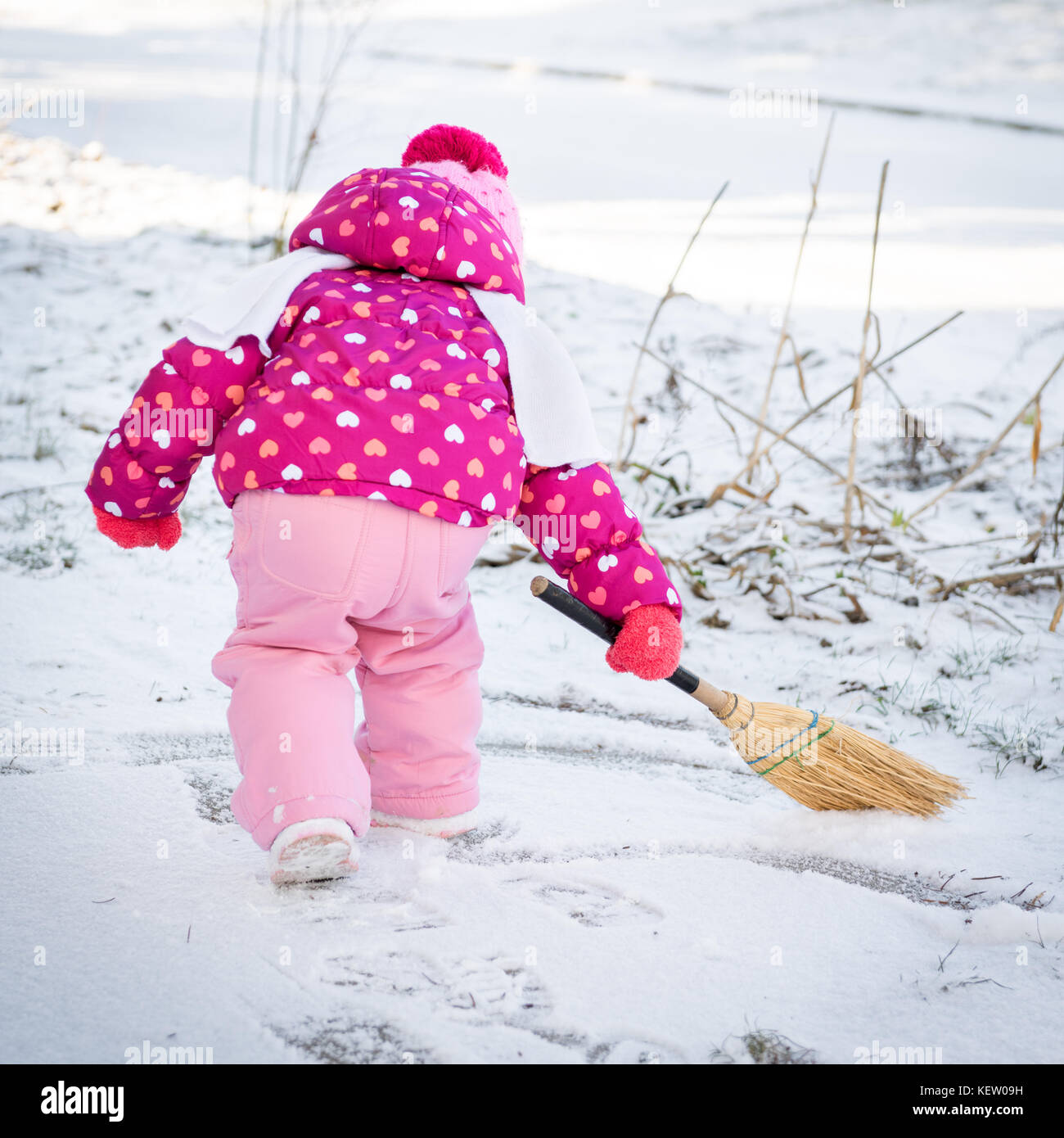 Süße kleine Mädchen spielen mit einem Besen außerhalb während der schneereichen Winter Tag Stockfoto