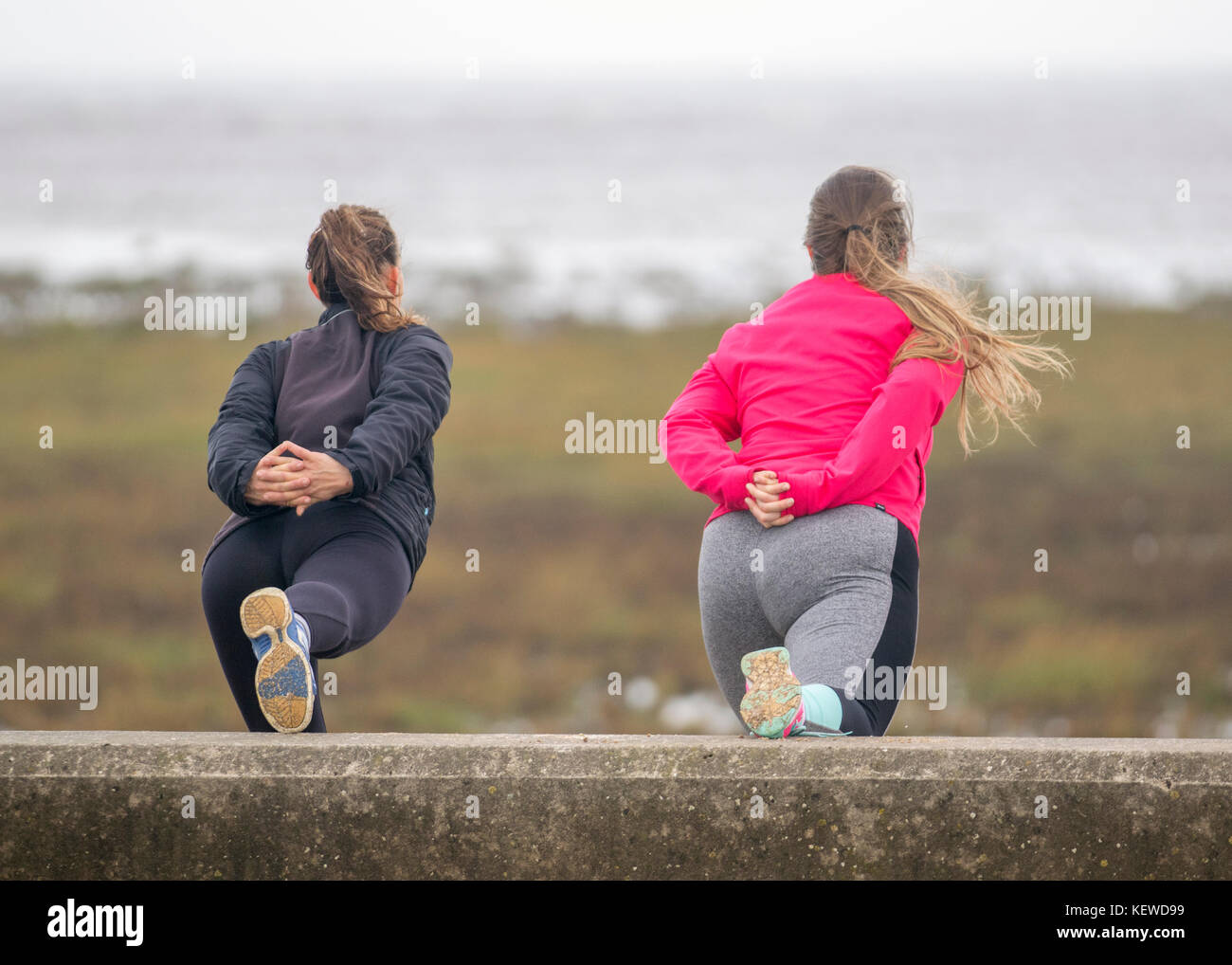 Rückansicht der Damen das Training in Southport, grau, regnerisch beginnt der Tag, als zwei Lasses auf der Promenade hinauflimbren, bevor es zum Joggen über die Küstenpromenade geht. Kredit, Gutschrift: MediaWorldImages/Alamy Live Nachrichten Stockfoto