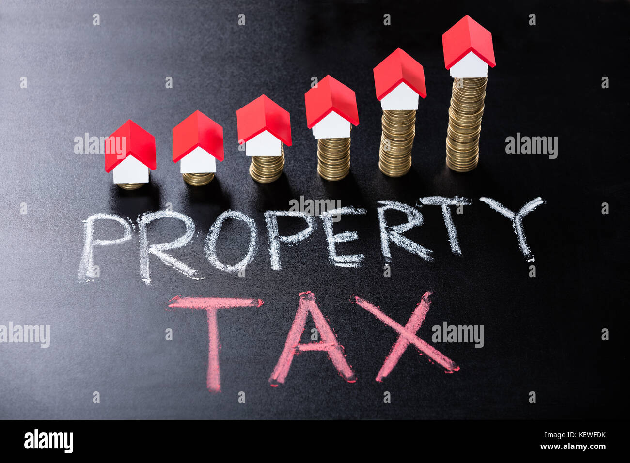 Haus Modelle auf Gestapelte Münzen übersicht Grundsteuer Konzept auf der Tafel Stockfoto