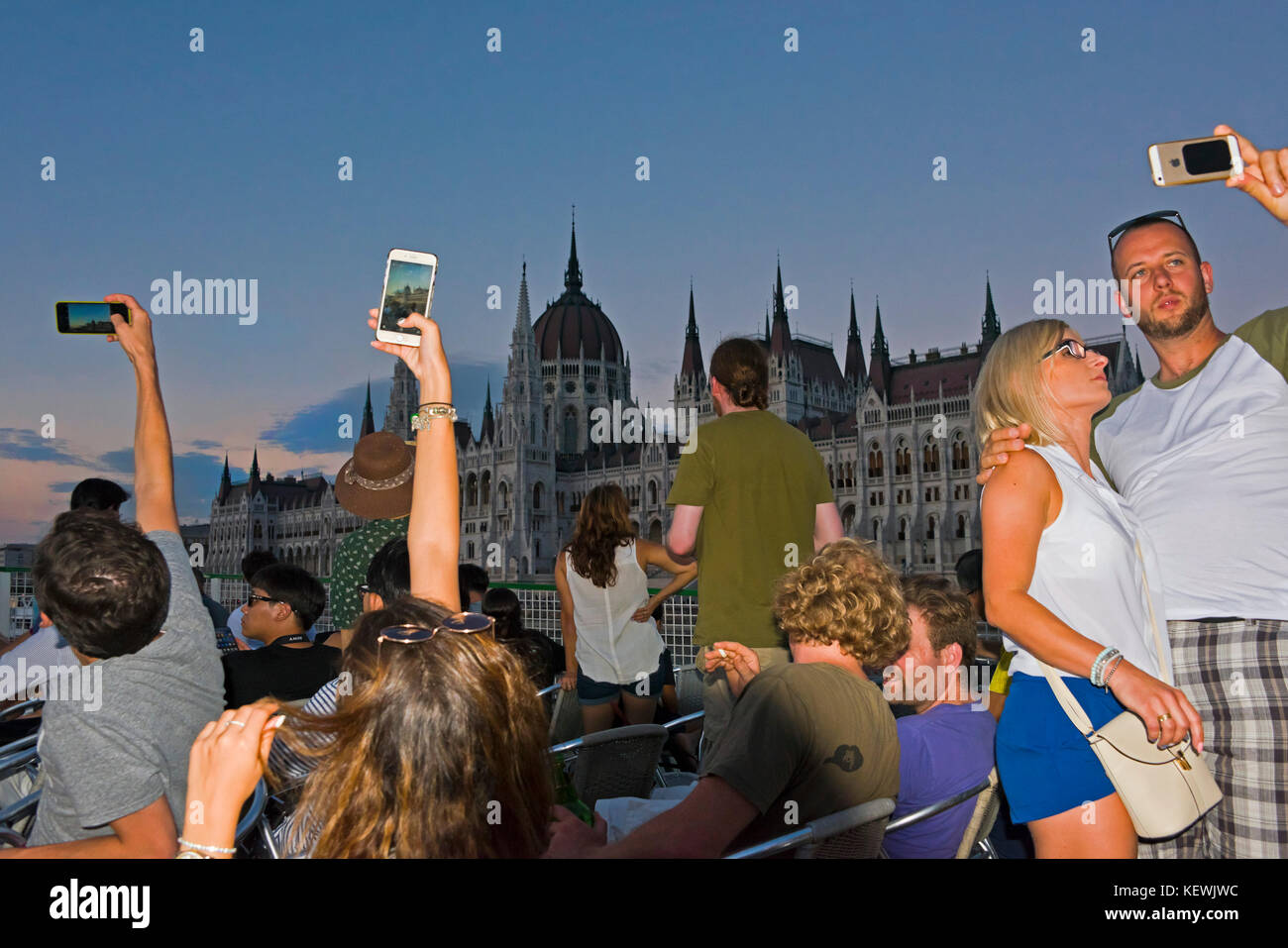 Horizontale Ansicht von Touristen an einem Abend Fluss Kreuzfahrt Fotos der Häuser im Budapester Parlament. Stockfoto