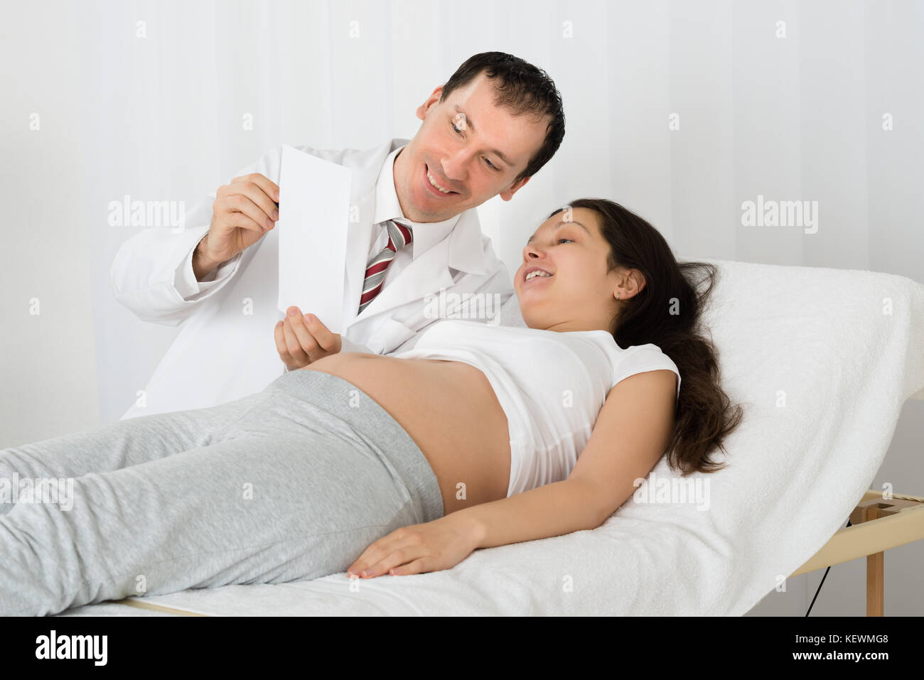 Männlicher Arzt mit Ultraschall für schwangere Frau in Klinik Scan Stockfoto