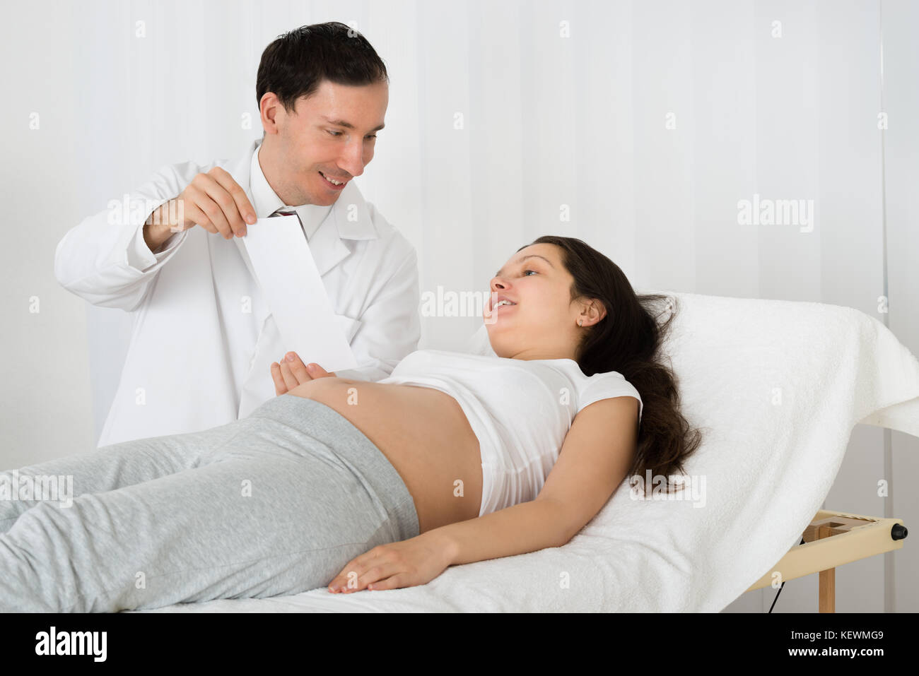 Männlicher Arzt mit Ultraschall für schwangere Frau in Klinik Scan Stockfoto