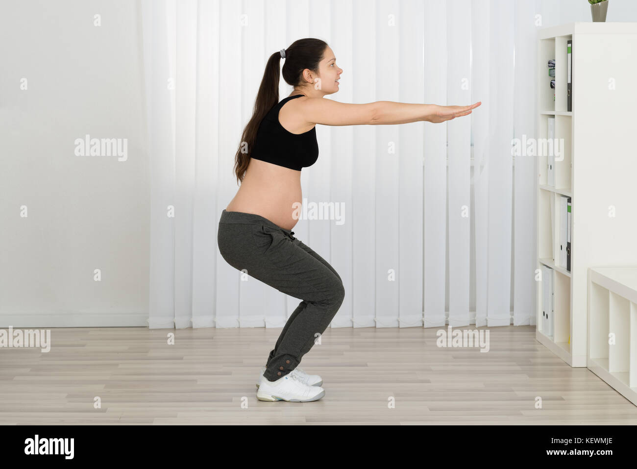 Junge schwangere Frau Training zu Hause Stockfoto
