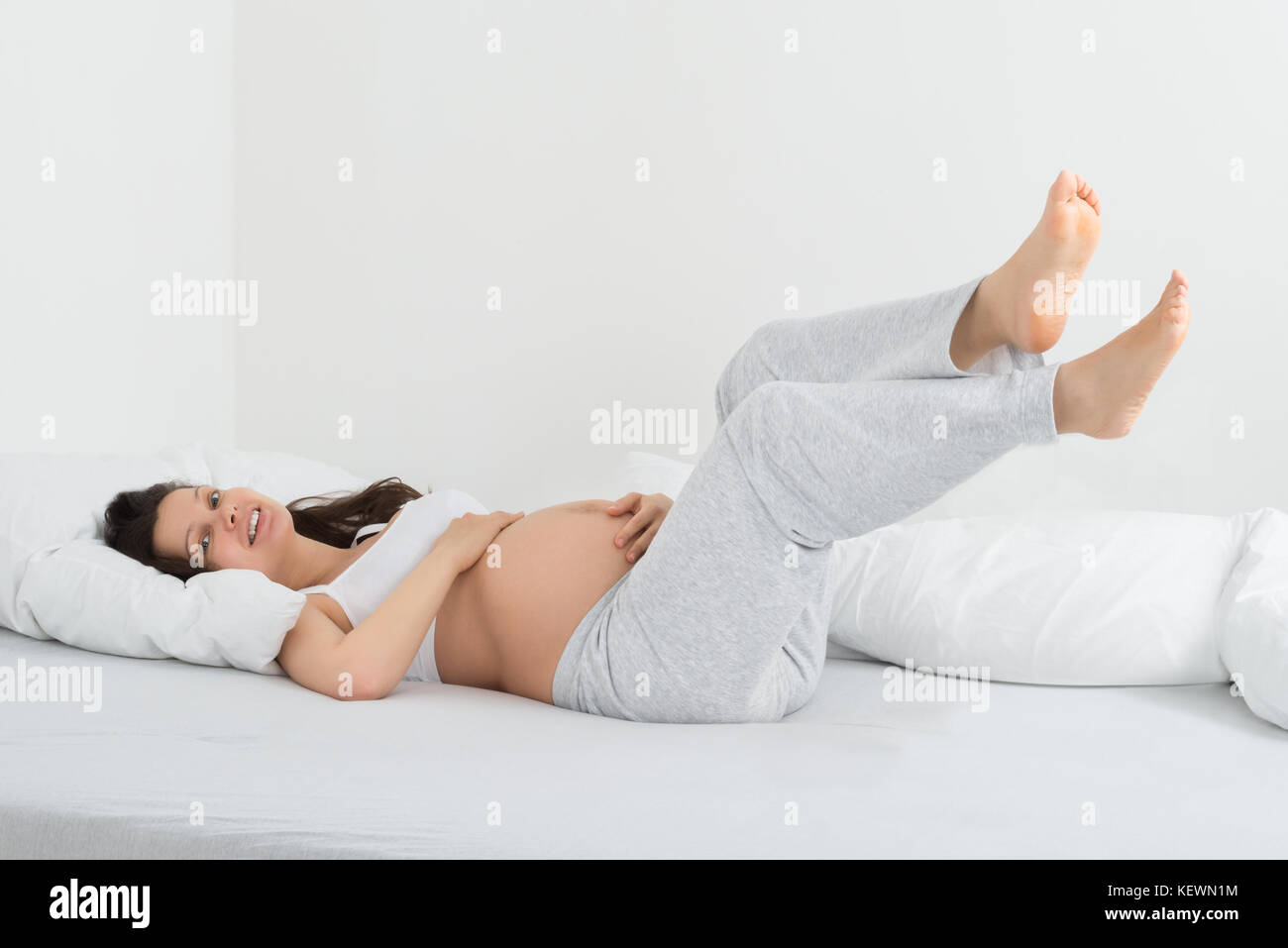 Junge glücklich Schwangere Frau entspannend auf dem Bett in Ihrem Schlafzimmer Stockfoto