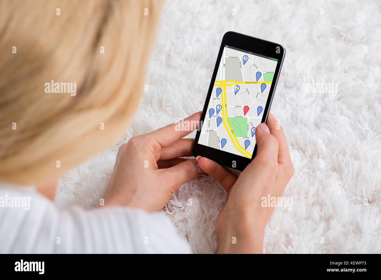 Nahaufnahme einer Frau liegend auf dem Teppich mit GPS Navigation Karte am Handy Stockfoto
